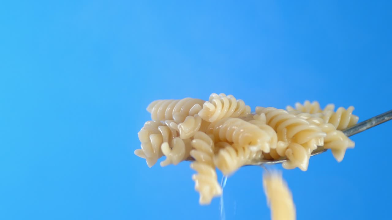 Hot boiled fusilli pasta falls from the ladle.