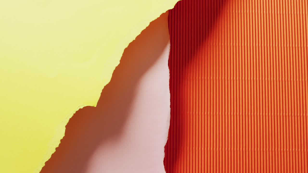 Video of close up of torn pieces of yellow, pink and orange striped paper background