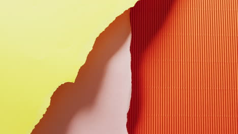 video of close up of torn pieces of yellow, pink and orange striped paper background