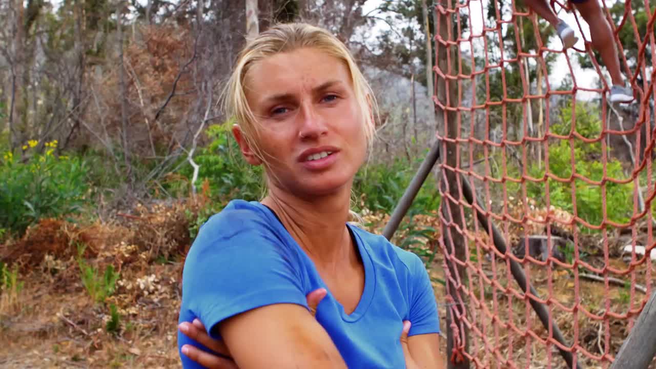 mujer feliz de pie en el campamento de entrenamiento con las manos cruzadas