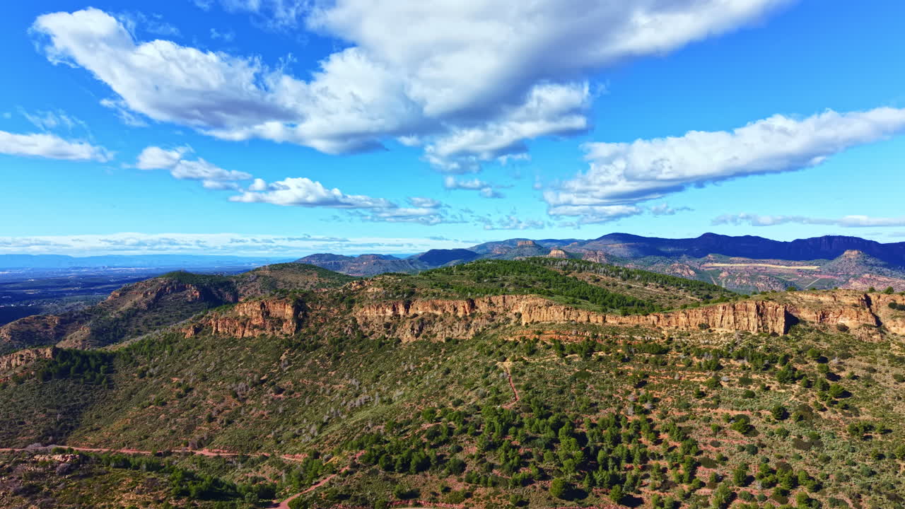 Montagne si ergono contro un cielo blu con nuvole e un paesaggio verde durante il giorno in un'area remota.
