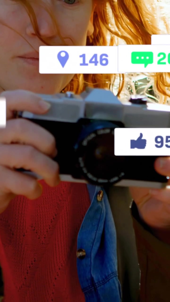 Vertikal video: Kvinde løfter kamera i solen, tapper på telefon og udløser sociale ikoner, der opnår rækkevidde