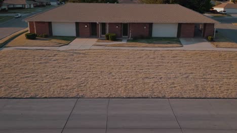 dry yellowed lawn grass in front of suburban terraced houses during sunset, symbolizing drought and water conservation issues in residential areas