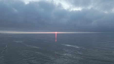witness the breathtaking beauty of a vibrant sunset illuminating the horizon over tranquil waves. seagulls roam the skies as day transitions to night
