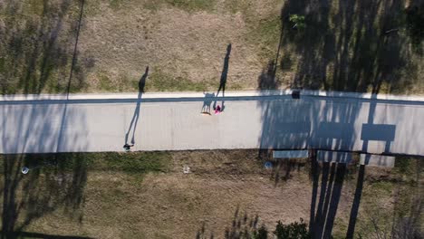 aerial-view-of-a-paved-road-with-people-running-and-walking-with-the-dog