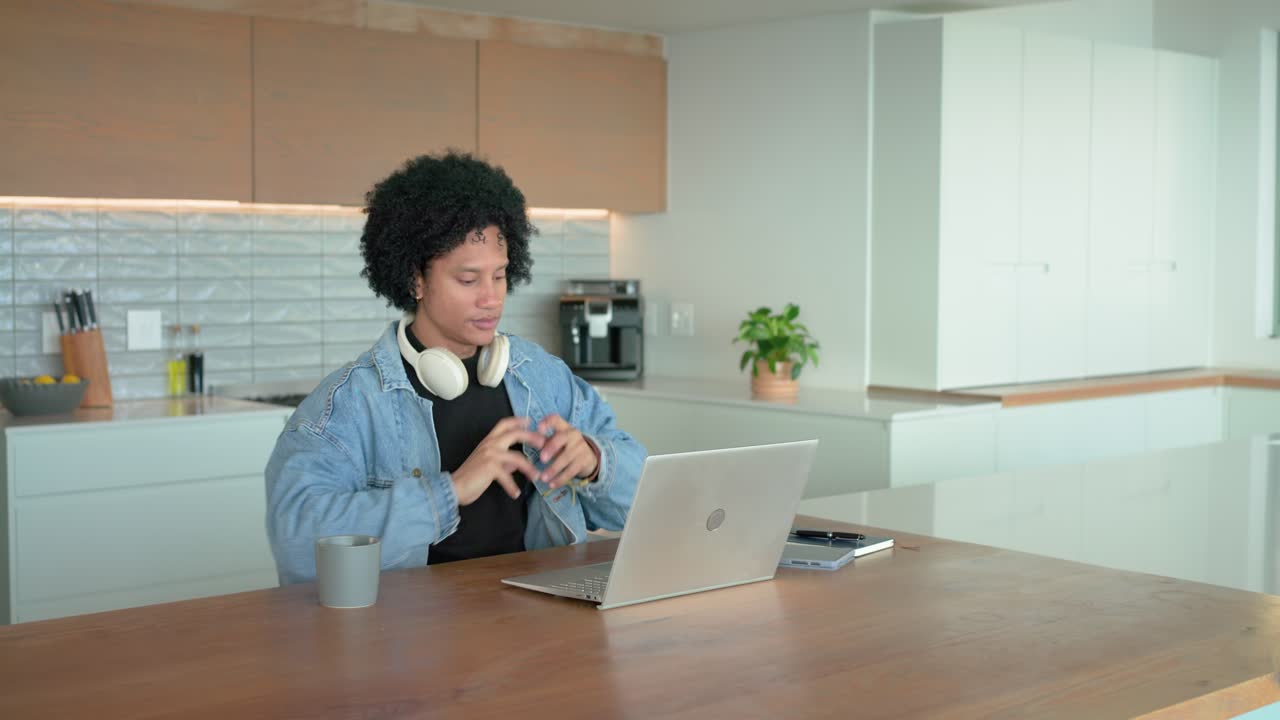 After typing man stretching at kitchen sipping coffee adjusting headphones resuming laptop typing