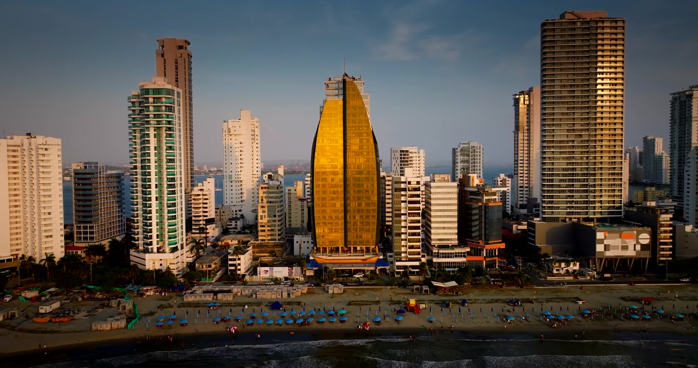Grattacieli moderni, hotel e spiaggia nel quartiere di Bocagrande durante l'ora d'oro a Cartagena, Colombia. Veduta laterale aerea con drone