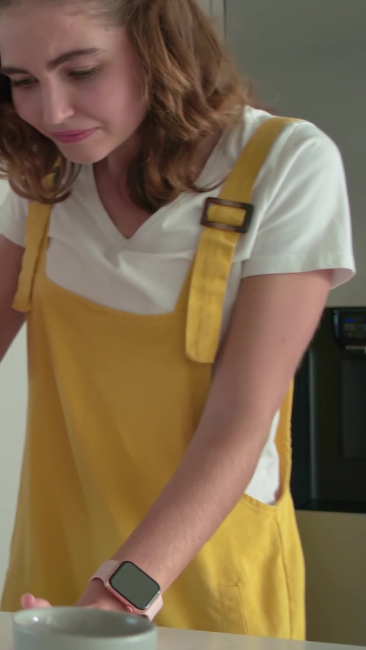 Video verticale: Vedendo la torta, donna in abito giallo che prende una tazza sul bancone della cucina, con spazio per il testo