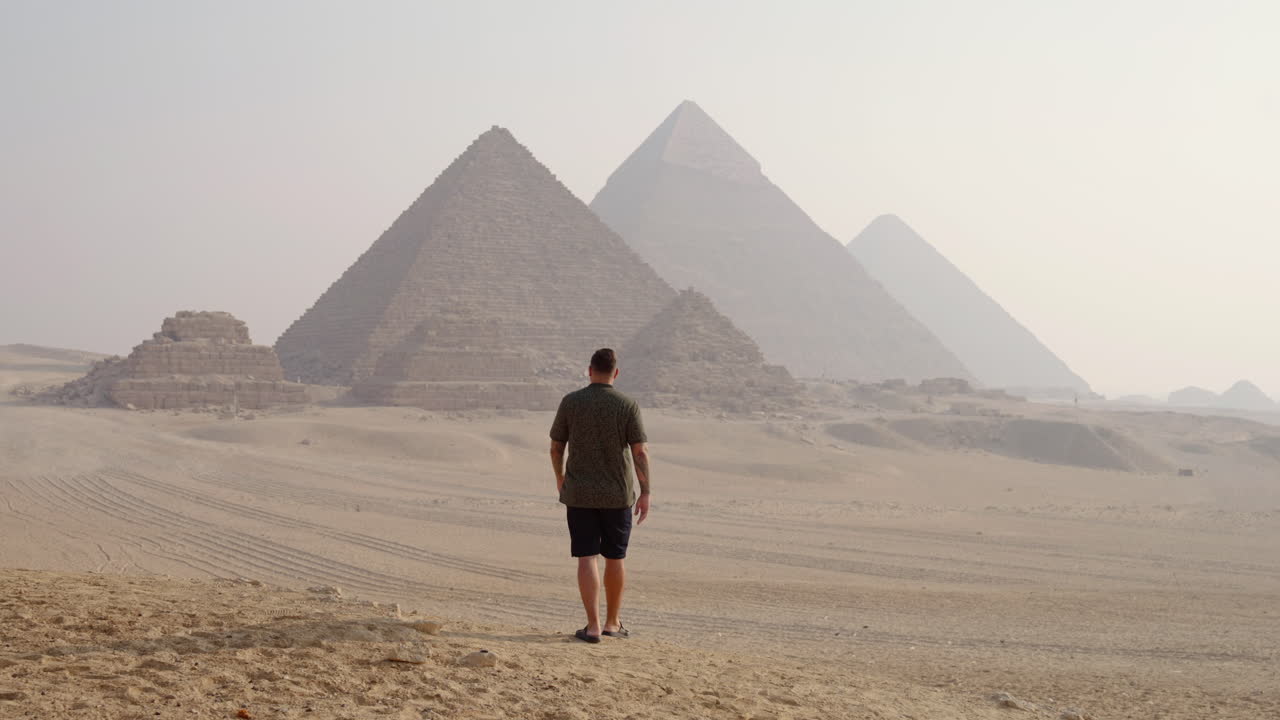 A Man Walking on the Giza Plateau With Views of the Pyramids at Sunrise Near Cairo, Egypt - Tracking Shot