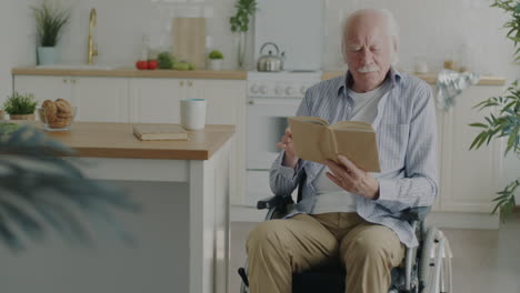 elderly man reading in wheelchair in kitchen