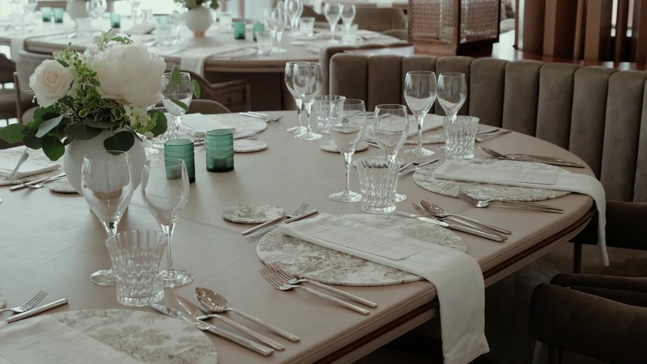 Wedding table set with crystal glasses cutlery linen napkins and a white rose centerpiece