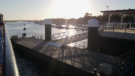 ferry pulls up to dock at sunset as deck hand ties off at olhao marina, portugal