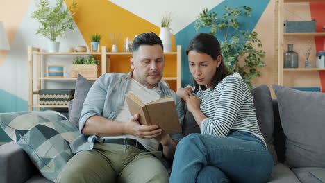 Couple Relaxing and Reading a Book Together on the Sofa