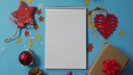 Video-of-christmas-decorations-with-notebook-and-copy-space-on-blue-background