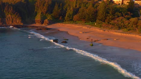 Person-Zu-Fuß-Am-Sandstrand-Von-Jones-Beach-Während-Des-Sonnenuntergangs-In-Kiama-Downs,-New-South-Wales,-Australien