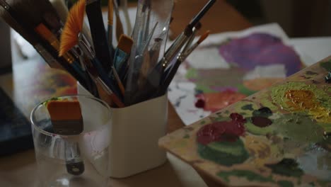 artist table full of colors, brushed and palette, motion close up view