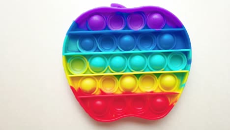 new baby toy. pop it finger play. funny color. colorful game spin on white table. rainbow apple shape