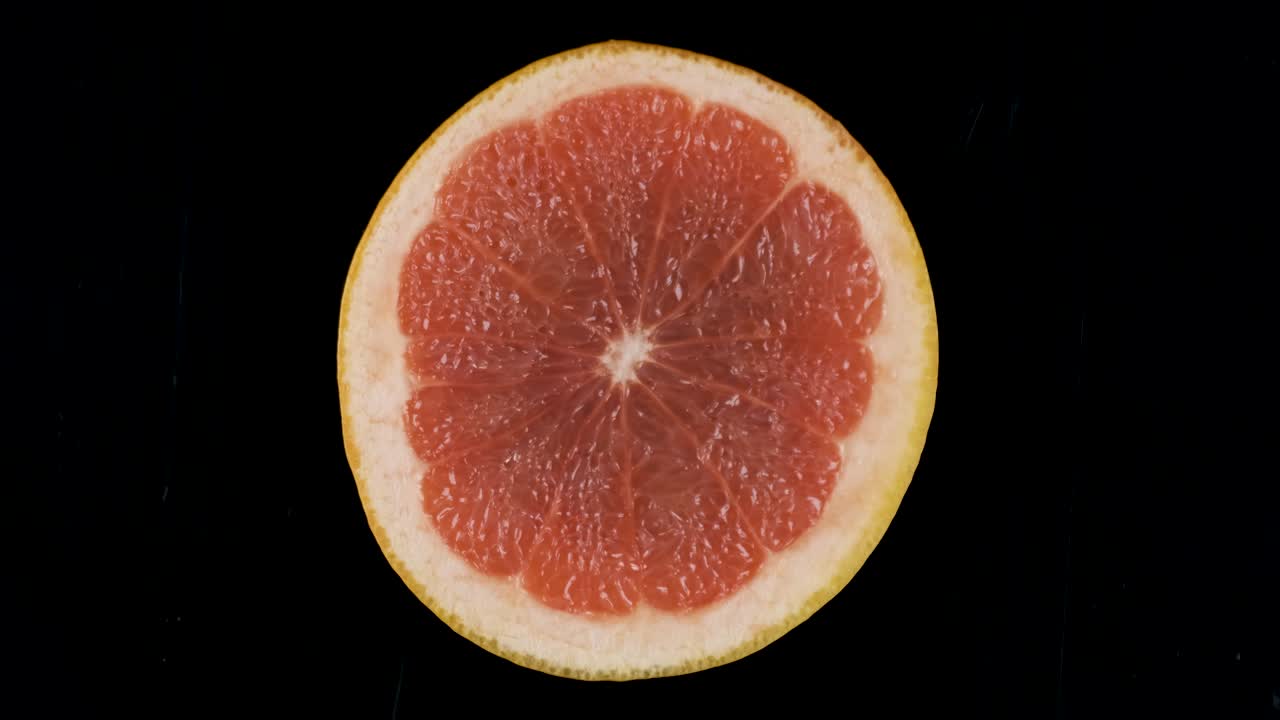 rotación de una rebanada de pomelo sobre un fondo negro.