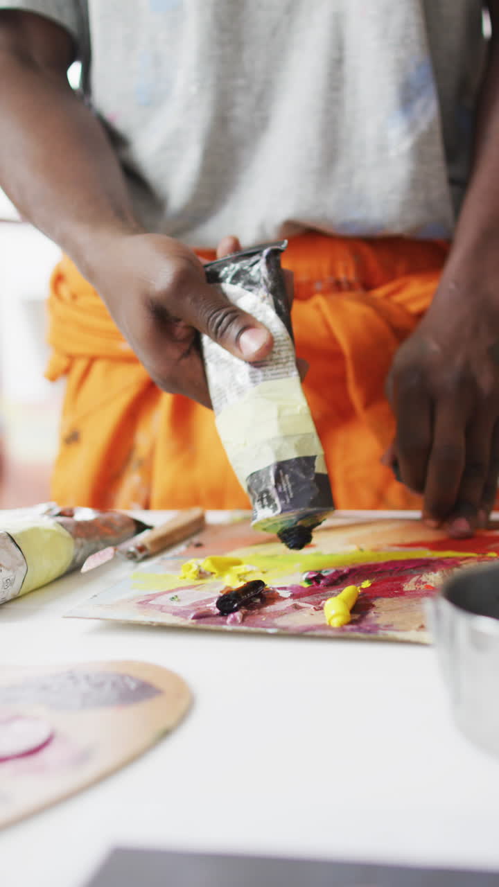 Vertical shot of an African American male artist mixing paint in a studio