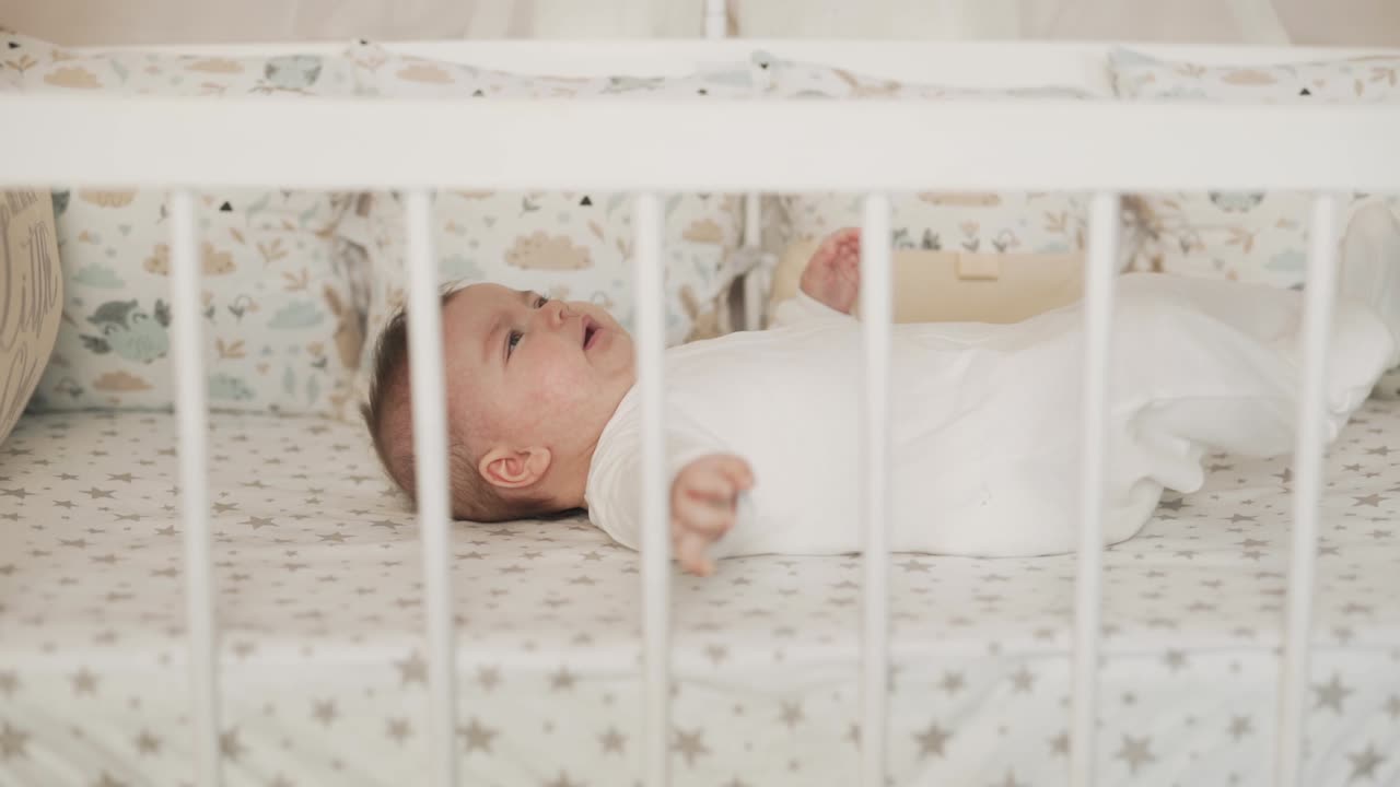 Vista laterale di una bambina piccola sdraiata nel letto e che guarda la fotocamera