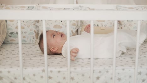 side view of a little baby girl lying in bed and looking at the camera