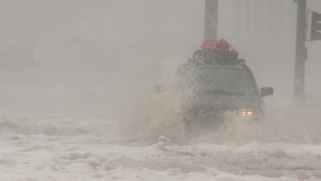 un automóvil conduce a través de aguas profundas durante las inundaciones de una tormenta o huracán masivo
