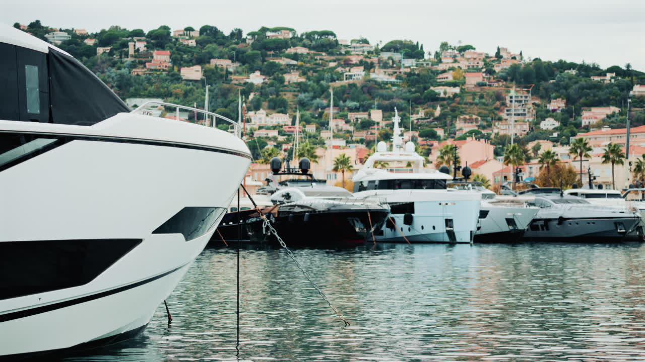 Yacht di lusso ormeggiati in un porto turistico tranquillo, con una pittoresca cittadina collinare sullo sfondo