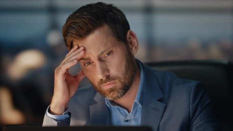 Exhausted manager massaging head at night office closeup. Tired director work