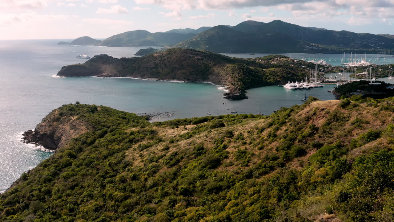 toma aérea de la puesta de sol en puerto inglés en antigua, caribe con vistas de yates, veleros, puerto deportivo, bahía y acantilados