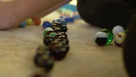 girl pulling a pile of marbles closer to a line of color sorted marbles