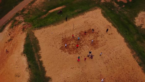 aerial orbit of a group of african man playing volleyball on a sand patch