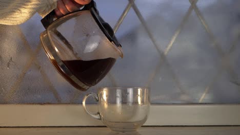 hand pouring freshly brewed hot coffee in winter window medium shot