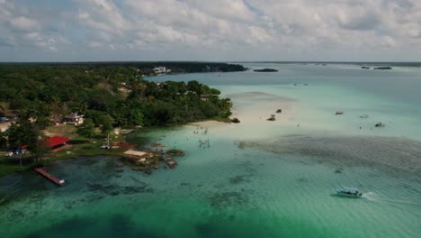 Aerial-shot-overseeing-the-white-sand-beaches-and-the-town-of-Bacalar,-Mexico