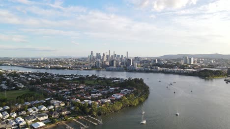 Veleros-Navegando-En-El-Río-Brisbane-A-Lo-Largo-Del-Suburbio-Bulimba-Con-Brisbane-Cbd-En-Segundo-Plano-En-Queensland,-Australia