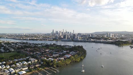 sailboats sailing at brisbane river along bulimba suburb with brisbane cbd in background in queensland, australia