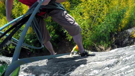 Rock-climber-adjusting-the-climbing-rope-while-climbing-the-cliff-4k