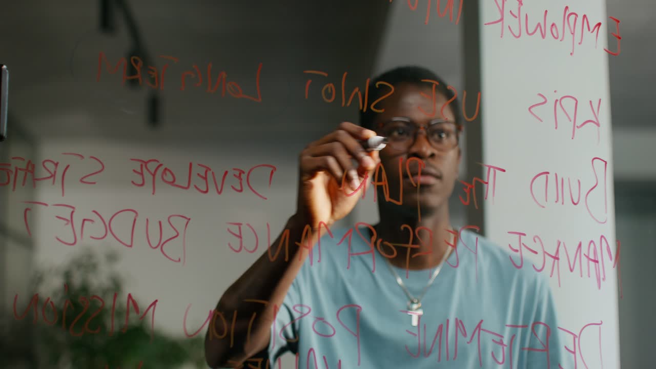 Man writing on a glass board during a meeting