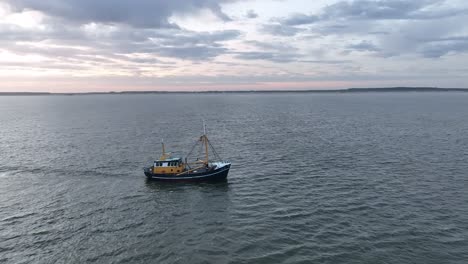 Schwenk-Drohnenaufnahme-Eines-Fischerboots,-Das-Die-Netze-Durch-Das-Wasser-Der-Küste-Von-Ameland-Zieht