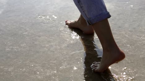 Woman-feet-walking-barefoot-by-lake-or-sea-shore-in-lins-flares