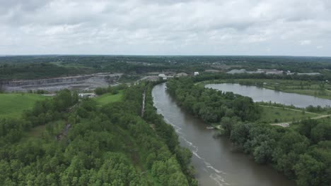 drone flies over a rolling river, over a forest, to a quarry in the midwestern usa