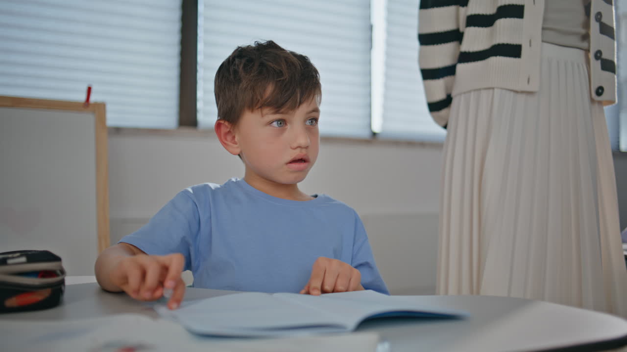 Small kid working diligently in notebook in elementary school class closeup