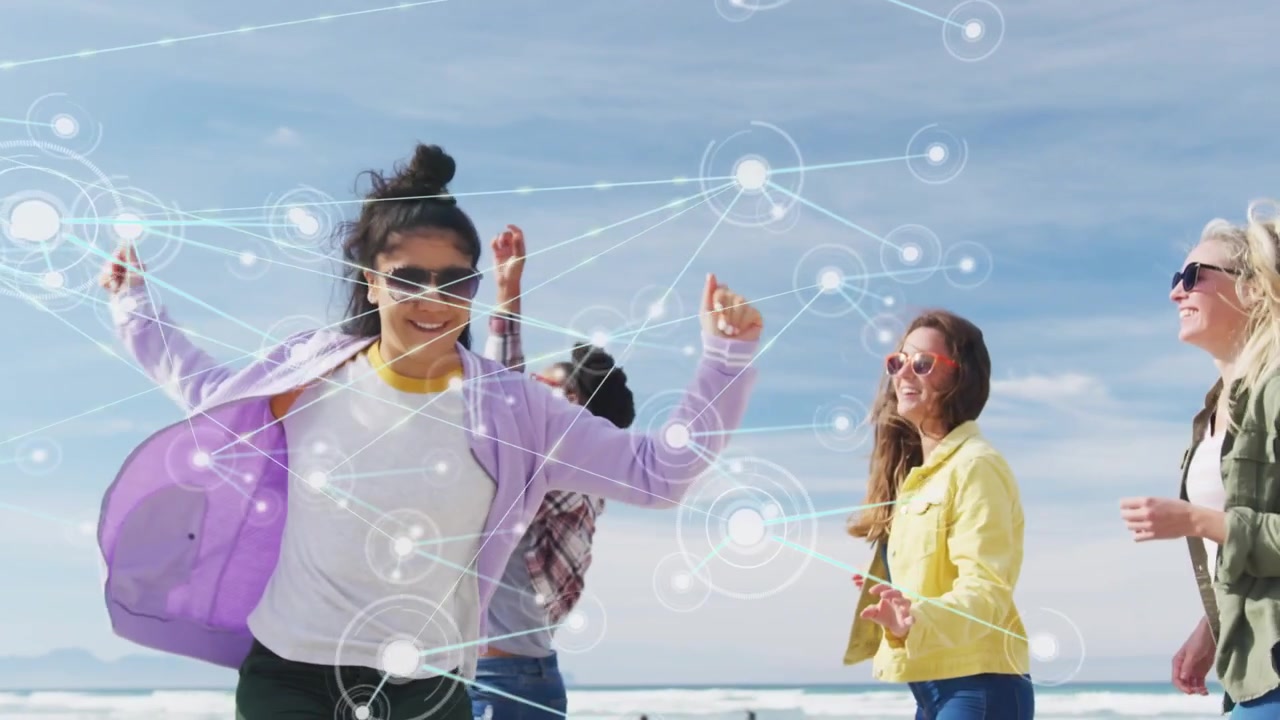 Quattro donne che giocano, girando sulla spiaggia, che avviano una rete tecnologica di nodi luminosi che si collegano attraverso il gruppo.