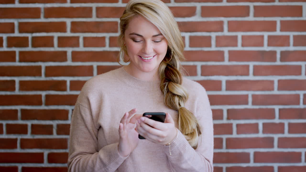 smartphone, donna felice e muro di mattoni