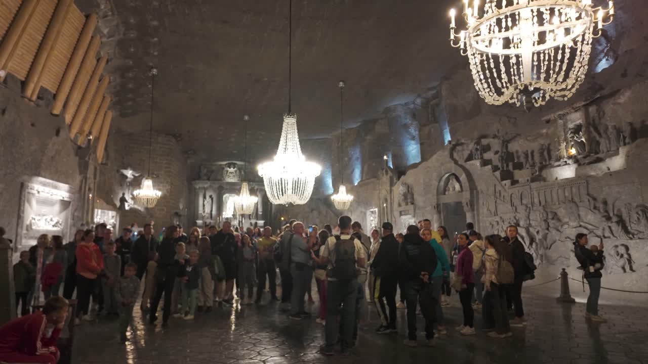 Main Hall of Salt Mines illuminated with visitors and scenic chandelier lighting inside as crowds gather