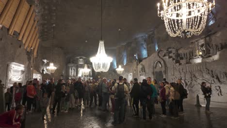 main hall of salt mines illuminated with visitors and scenic chandelier lighting inside as crowds gather