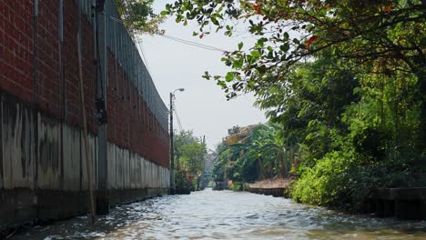 traveling along a canal in bangkok's lush floating market area