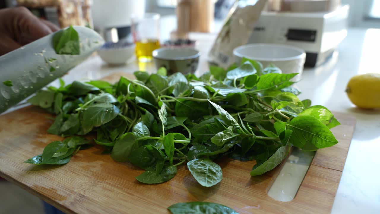 Man Chopping Fresh Basil on a Wooden Cutting Board