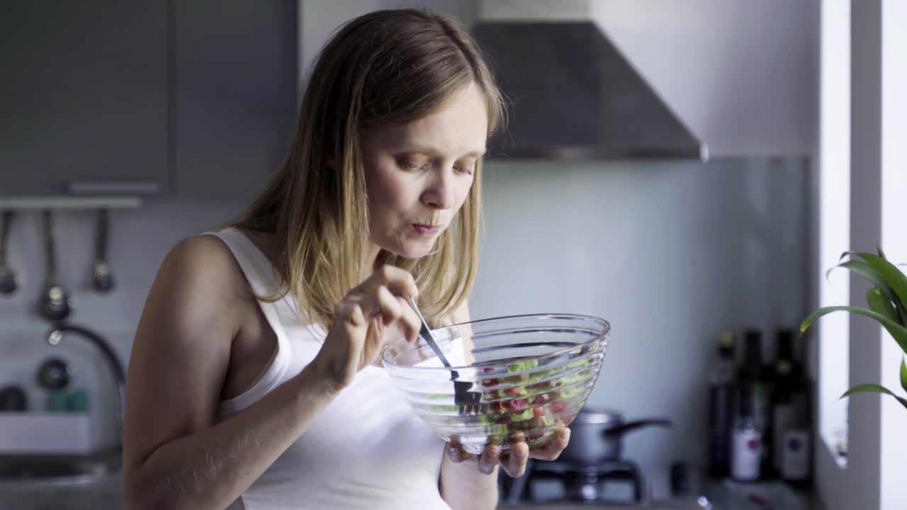 hermosa mujer embarazada comiendo ensalada y frotando el vientre