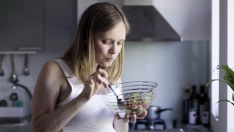 beautiful pregnant woman eating salad and rubbing belly