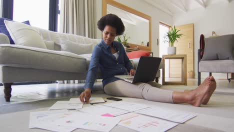 Glückliche-Afroamerikanische-Frau,-Die-Auf-Dem-Boden-Sitzt,-Einen-Laptop-Benutzt-Und-Arbeitet